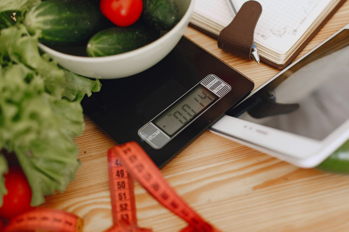 Digital scale and measuring tape with household items, illustrating measurement systems used in daily life.