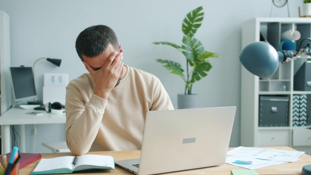 Overwhelmed person working at a laptop, illustrating decision fatigue symptoms.