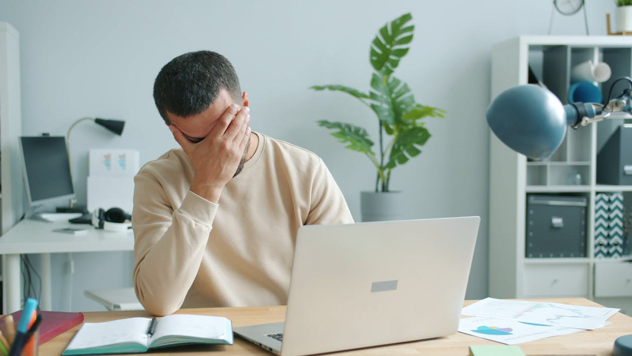 Overwhelmed person working at a laptop, illustrating decision fatigue symptoms.